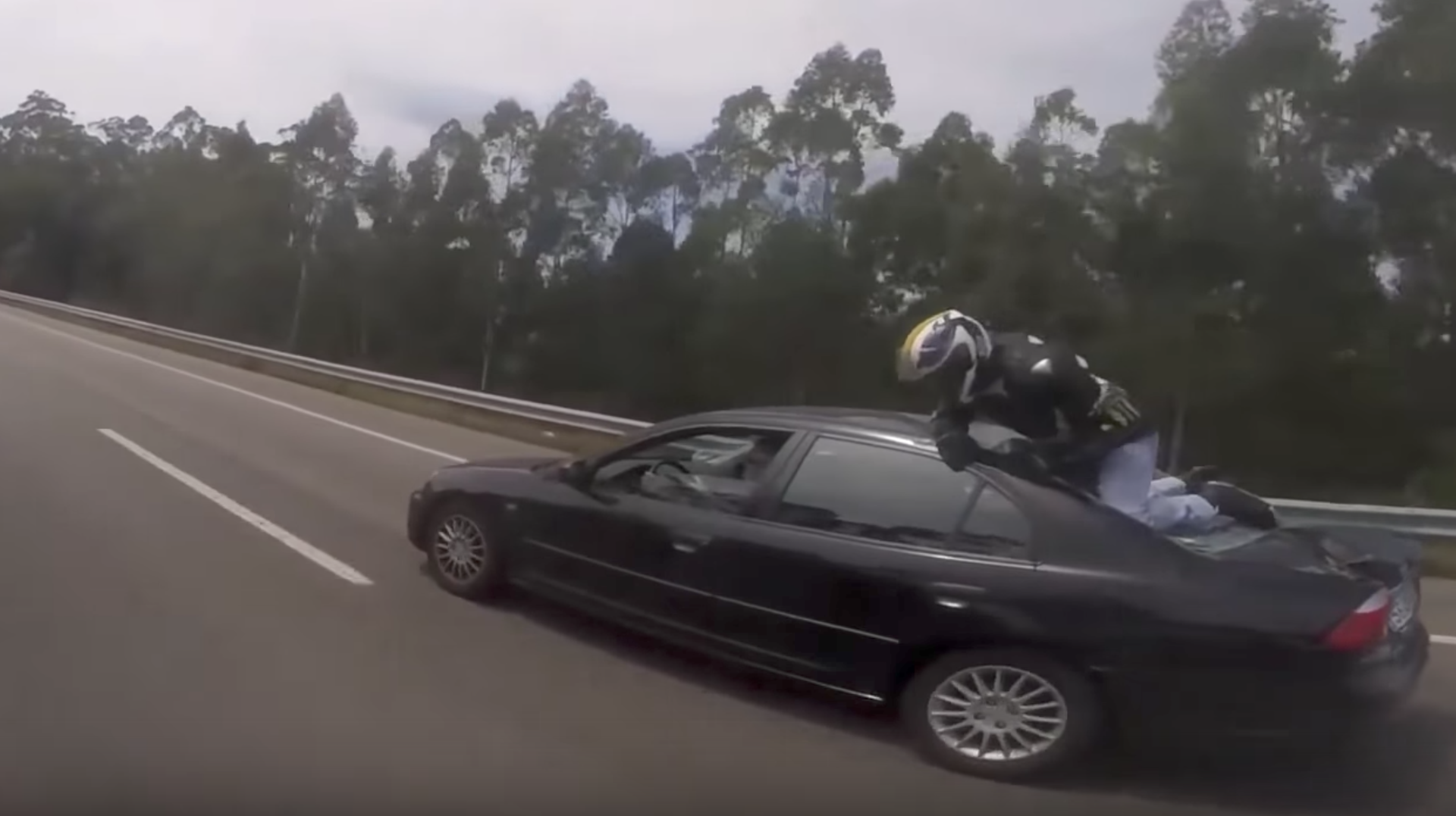 Watch This Motorcyclist Cling to a Car After Falling Off Bike on a Highway
