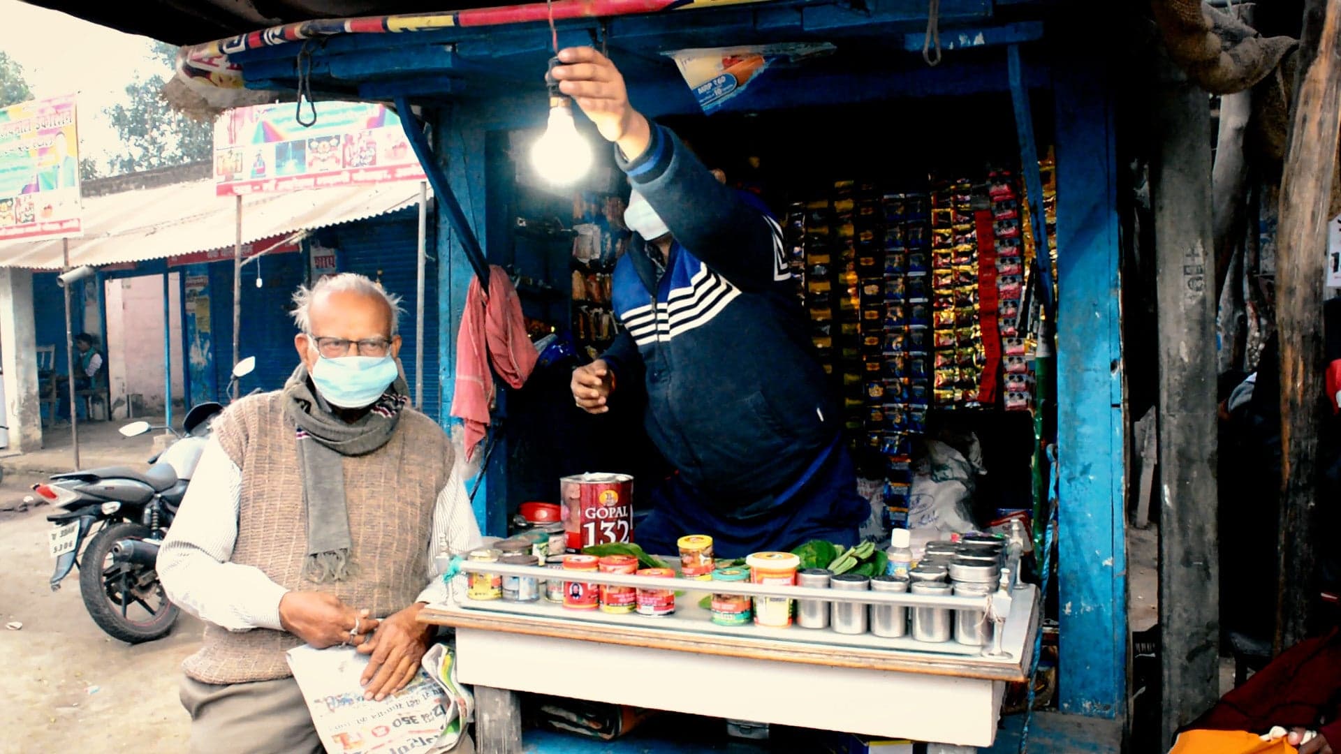 Shopkeepers at a market in Uttar Pradesh, with a light on that's powered from the solar microgrid