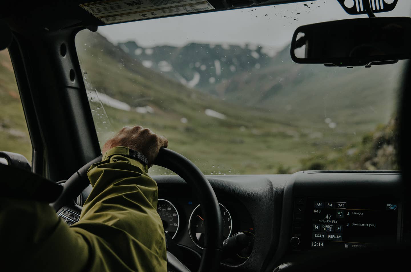 A person driving their car through a series of green mountains