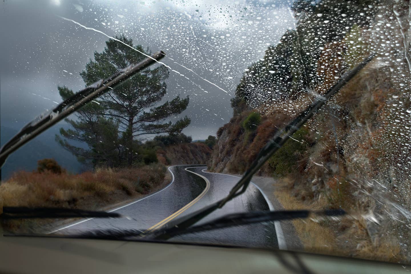 Windshield being cleaned by wiper blades during heavy rain and wind