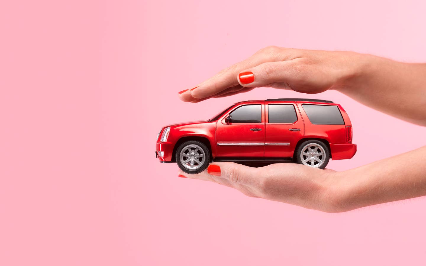 A hand holding a small car.