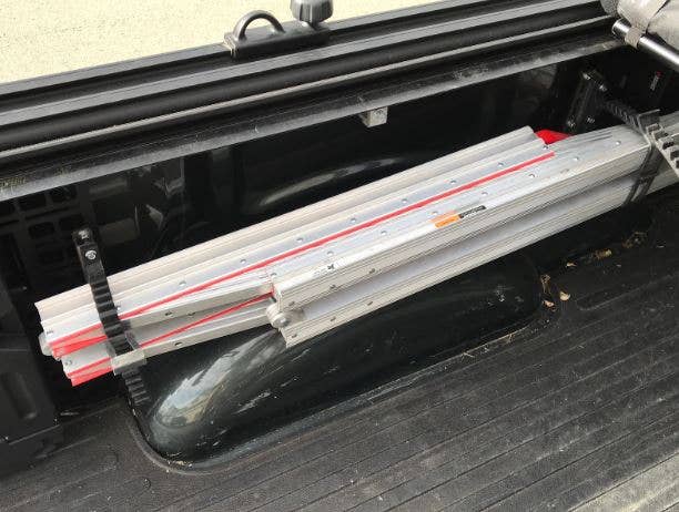 A folded ramp hanging on the side of a truck bed.