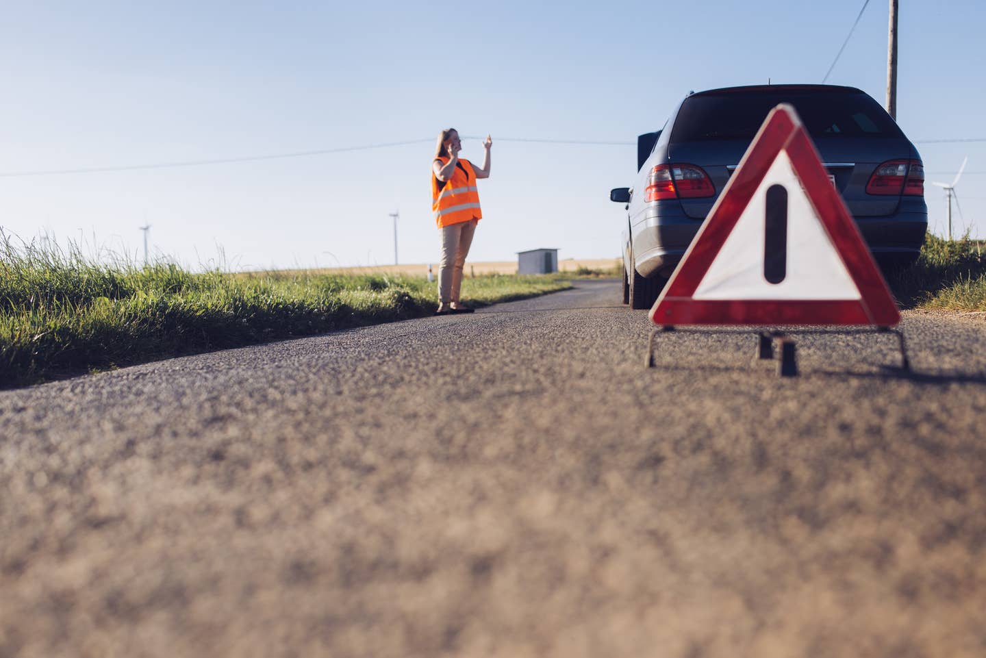 A woman with a broken down car on the side of the road.