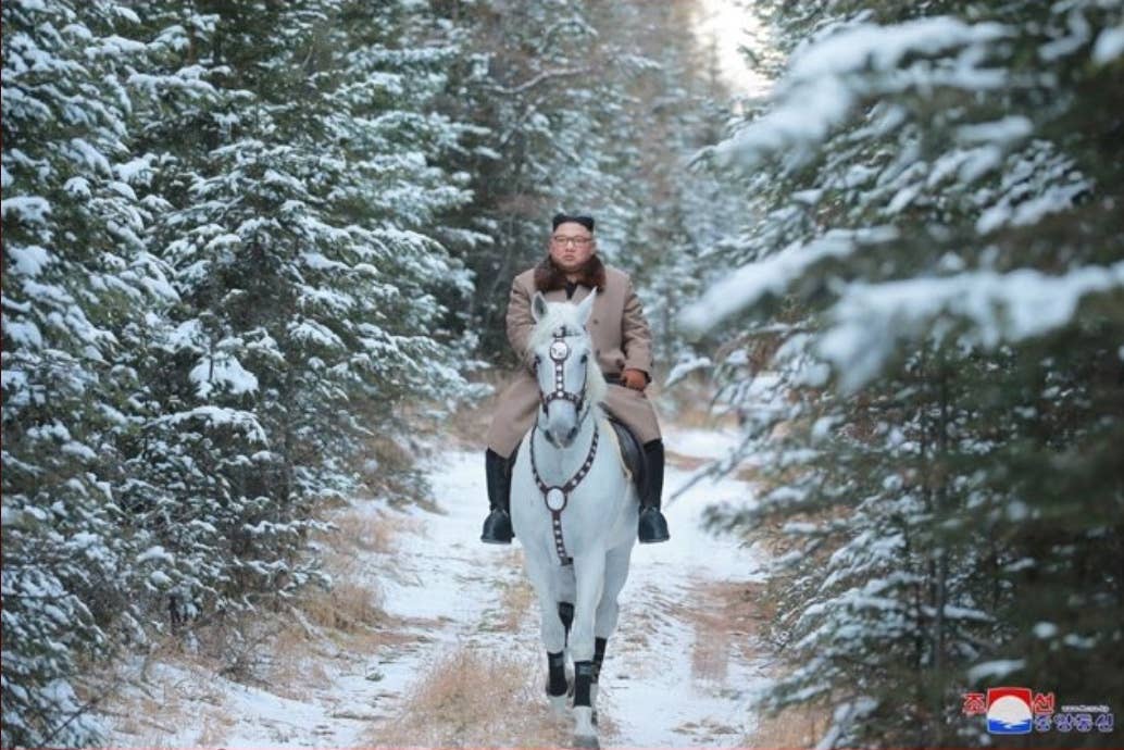 Kim Jong Un riding through a forest on a horse. 