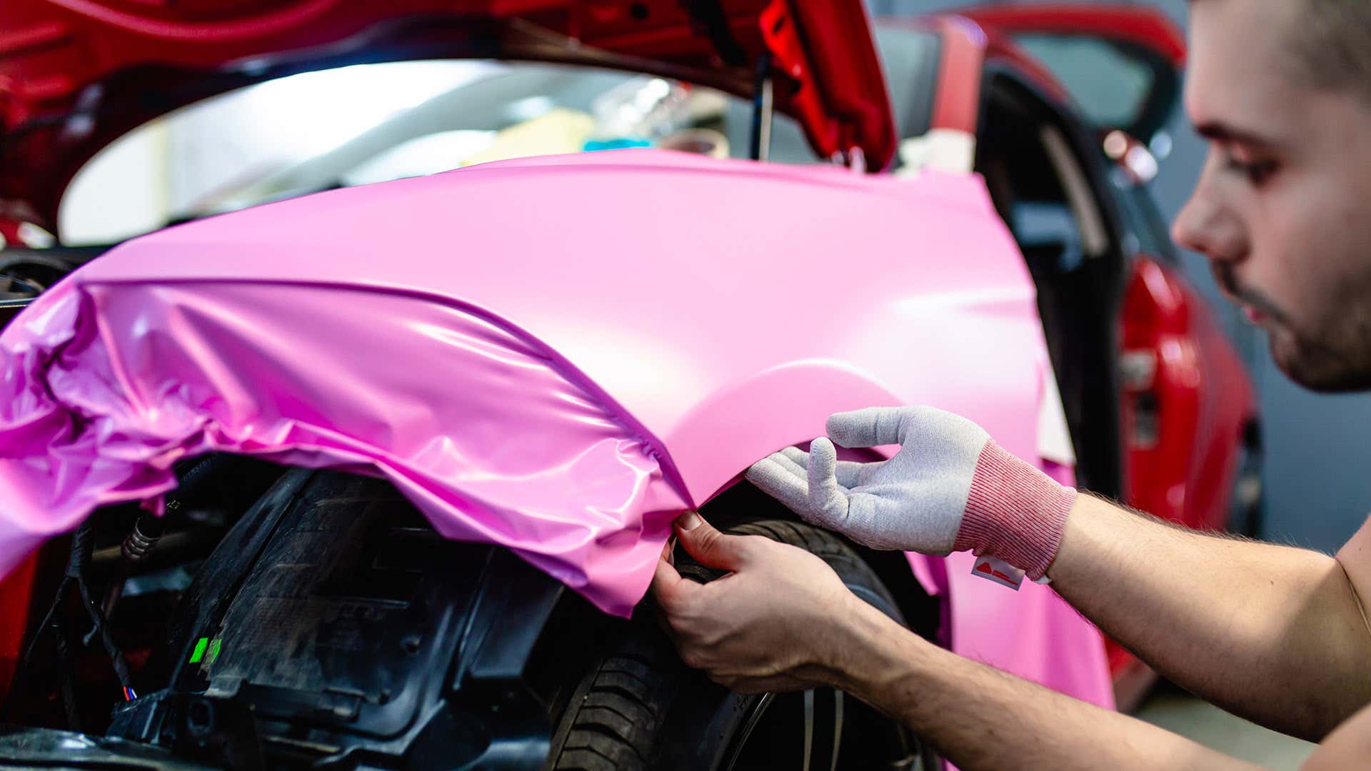 Installers use lintless gloves to apply vinyl wraps to cars.