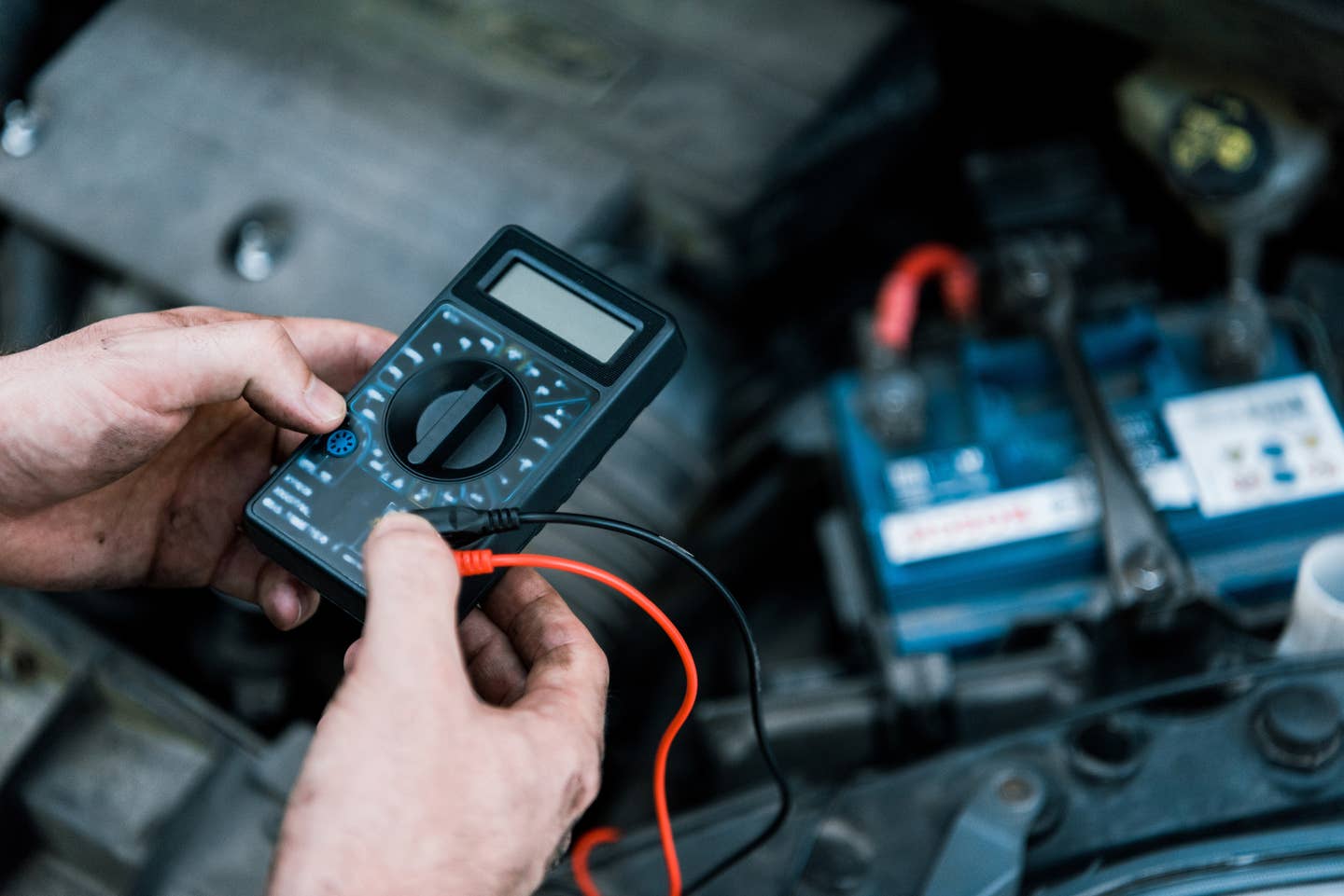 A mechanic testing a battery with a multimeter.