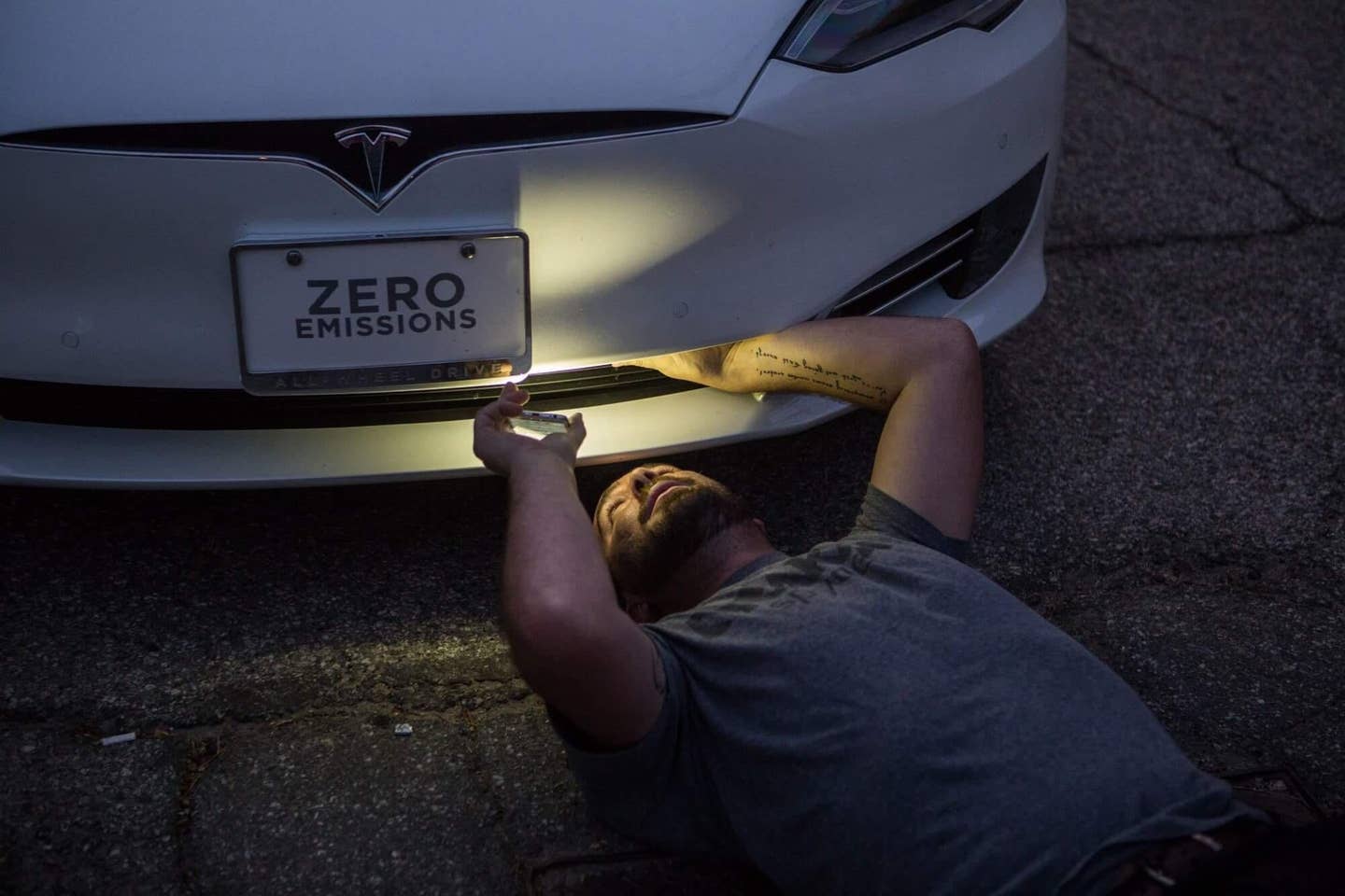A guy looks underneath a Tesla Model S.
