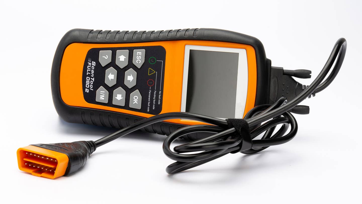 A black and orange OBD reader with the cord tied up.