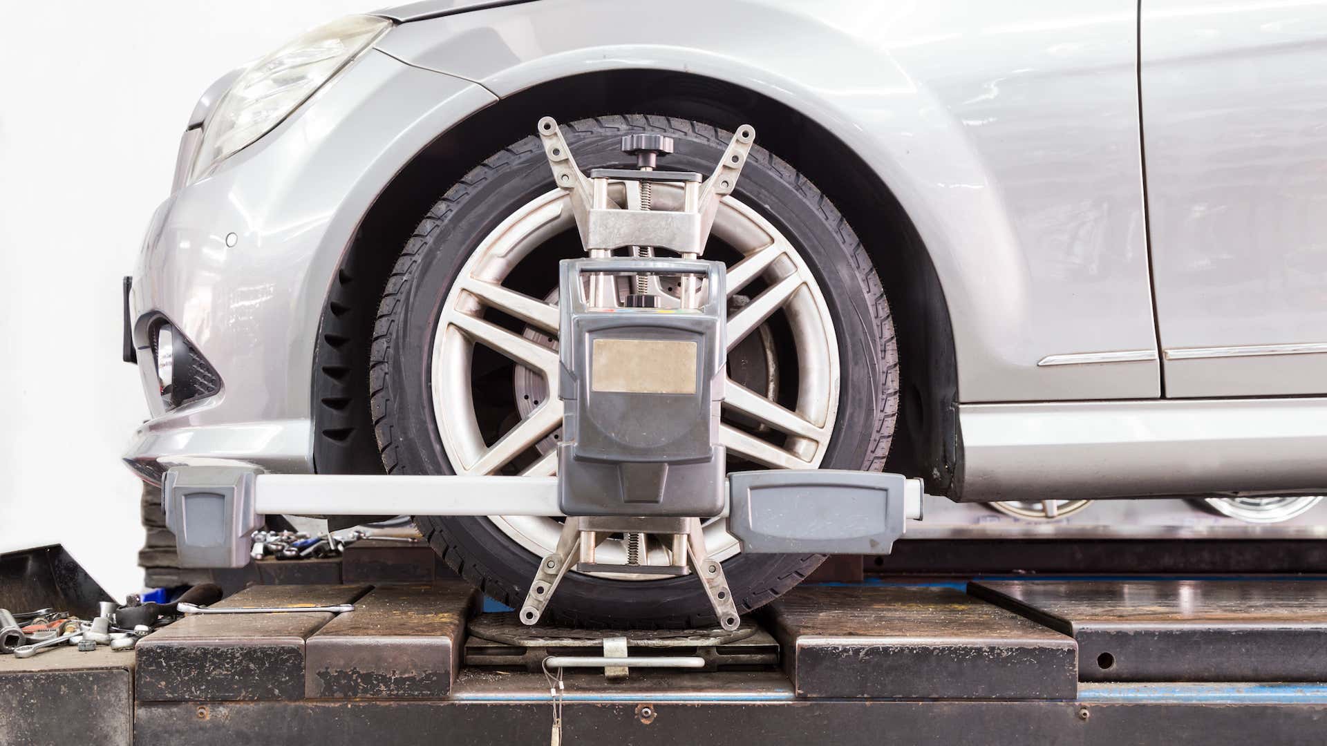 A wheel alignment tool is attached to the front driver's side tire of the car.