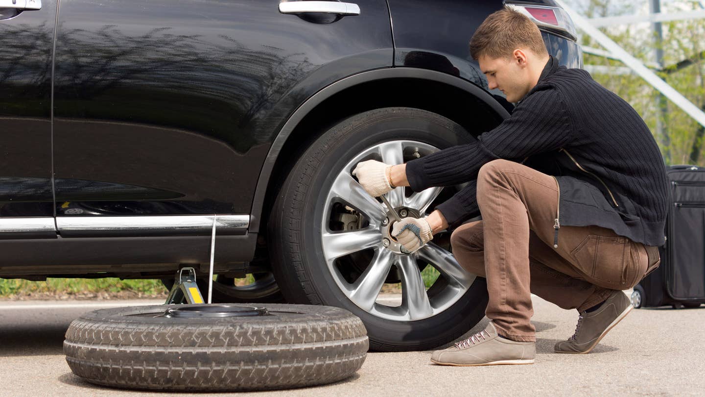 A man wrenches on lug nuts before installing a spare tire.