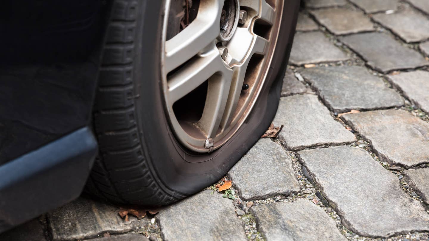 A flat tire sits on brick pavers.