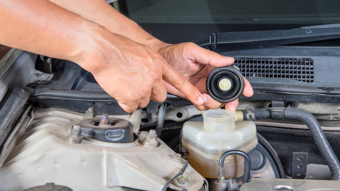 Person pointing to where brake fluid goes. 