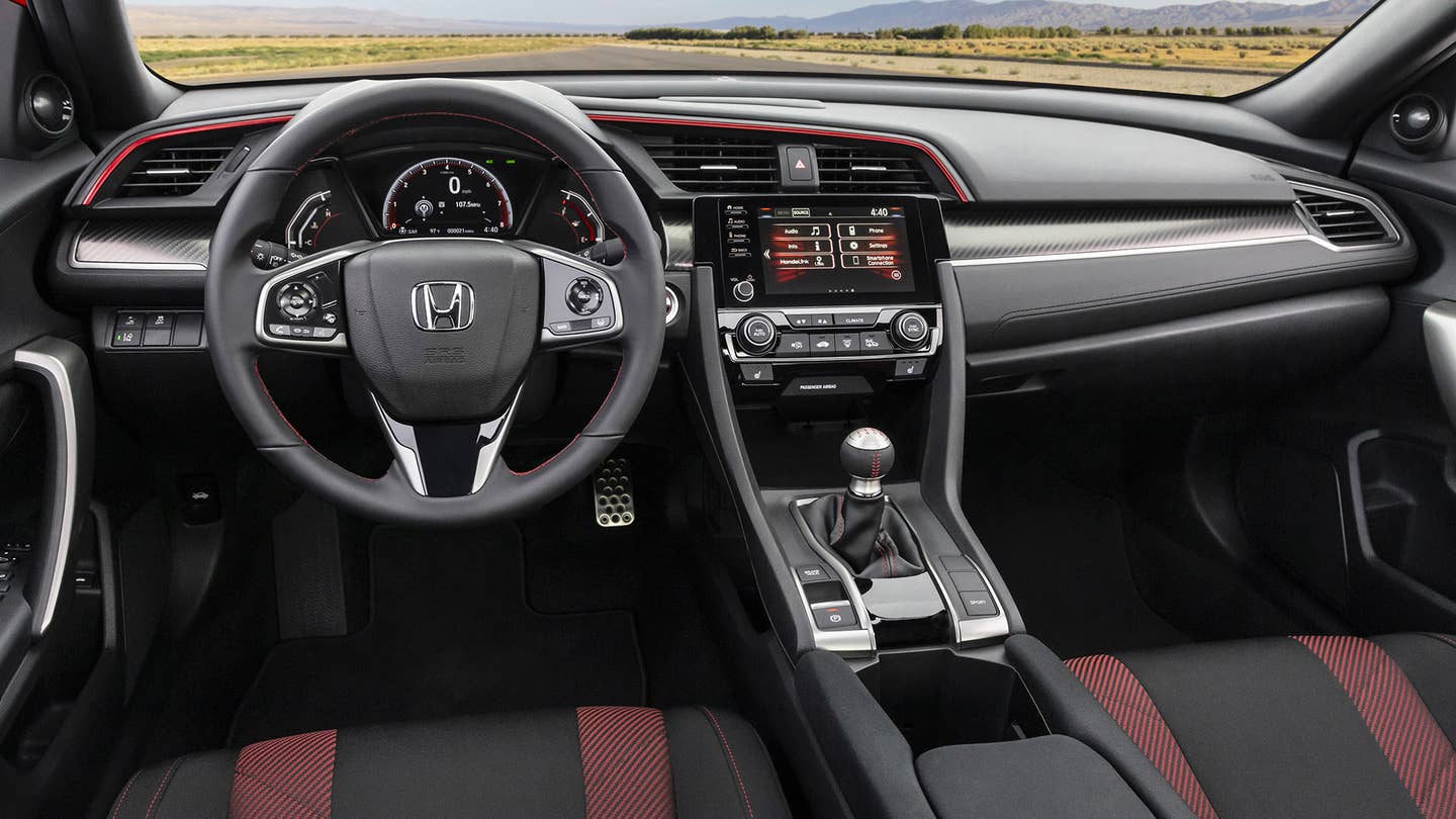The interior of a Honda Civic Coupe Si features a stick shift and red and black seats.