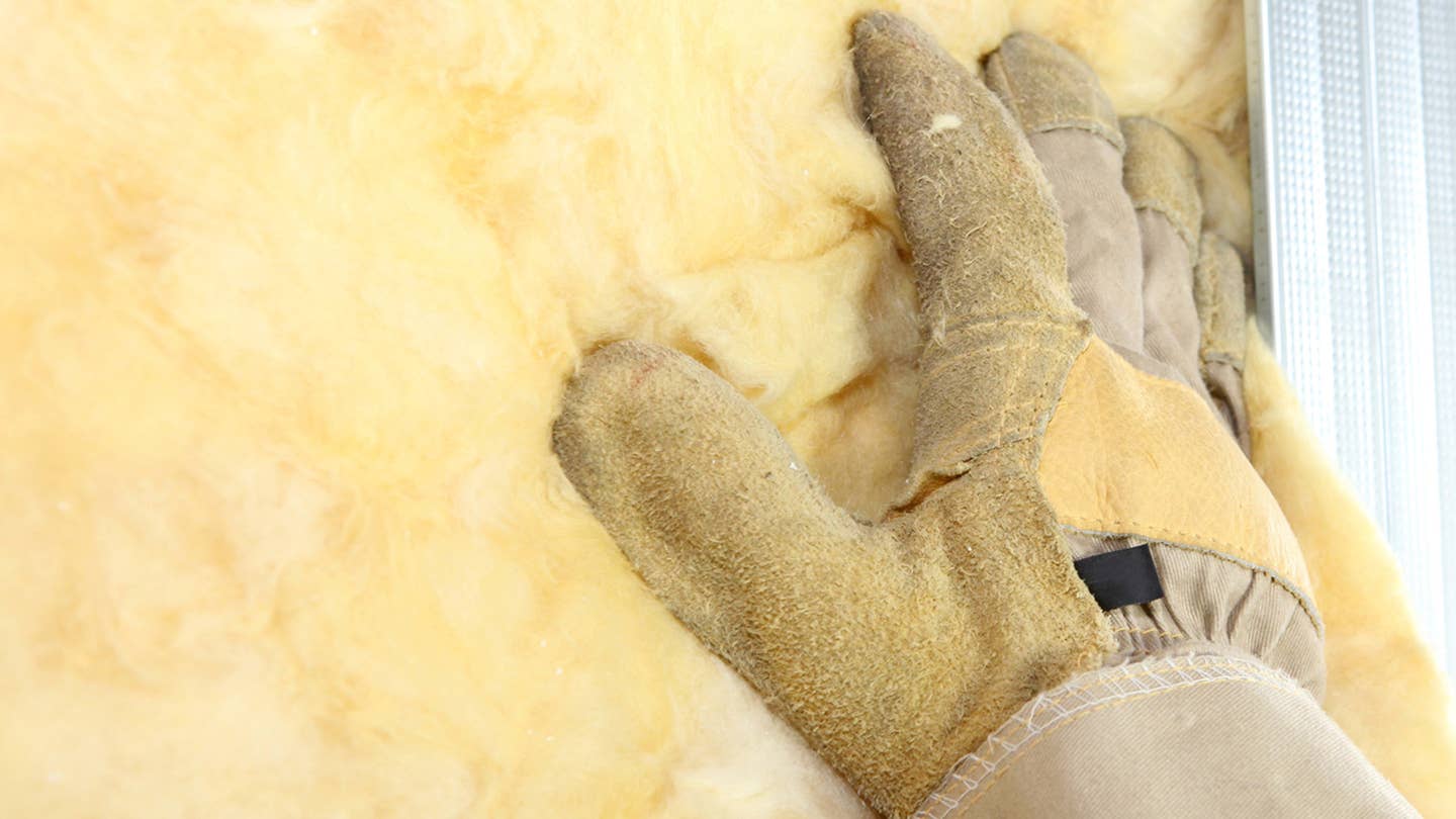 A sturdy work glove pats down insulation.