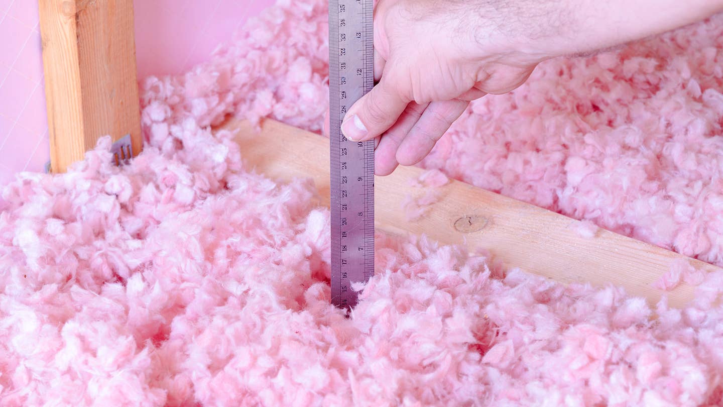 Pink free-form insulation is measured by a ruler.