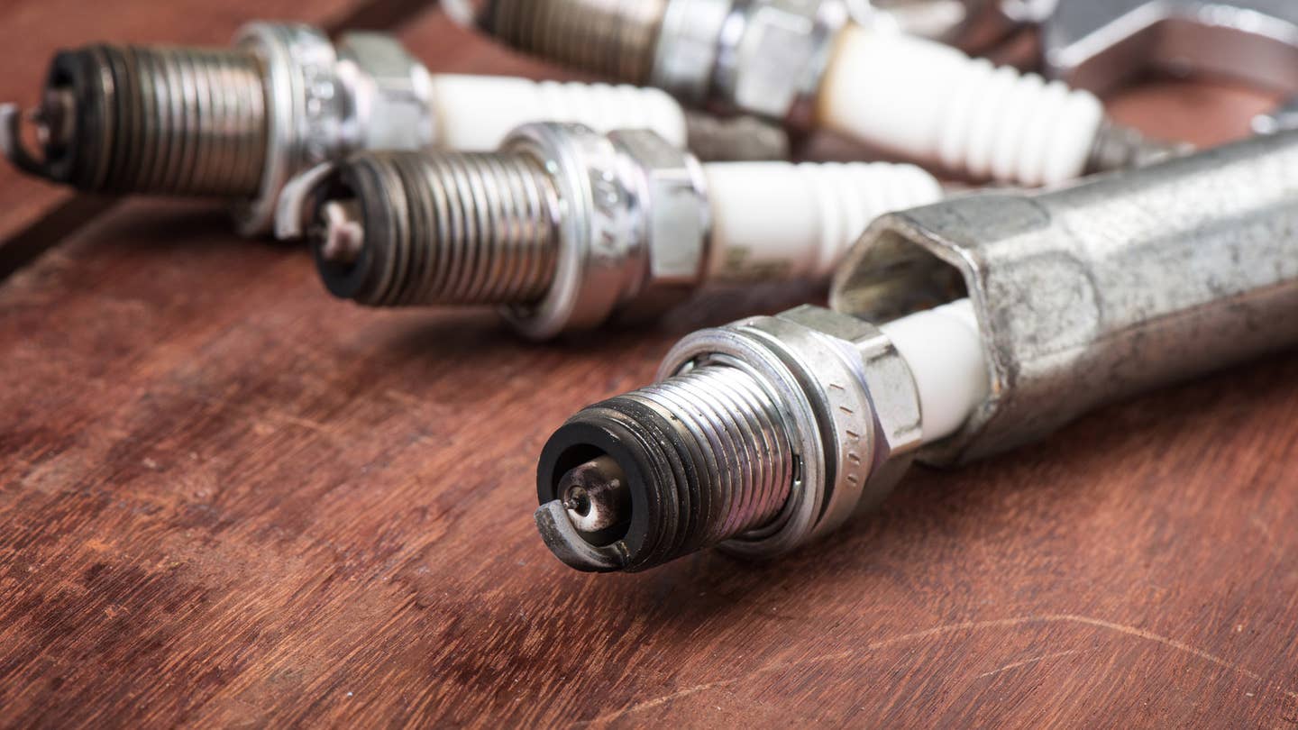 Bad spark plugs sit on a wooden table.
