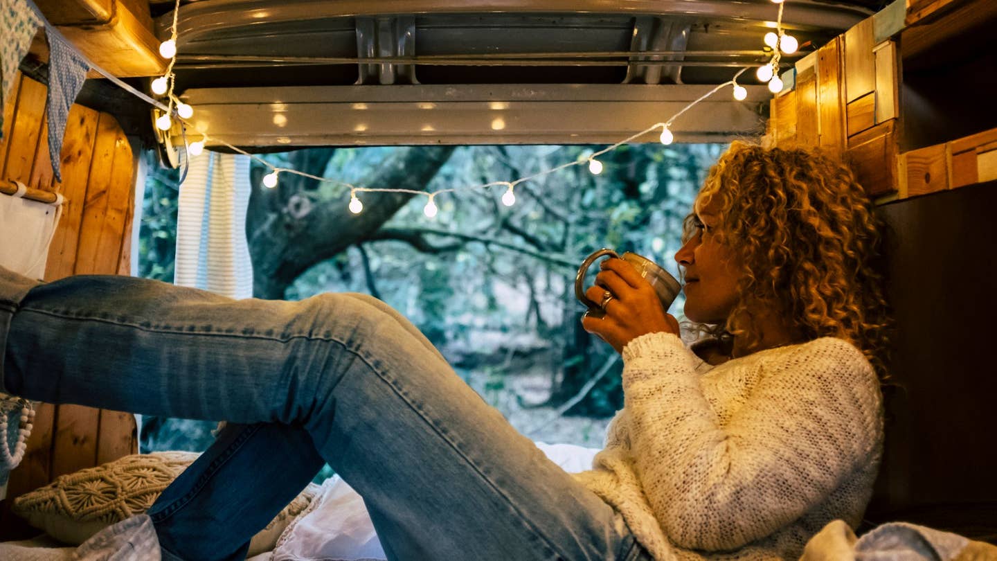 A woman enjoying some coffee in the morning from her van. 