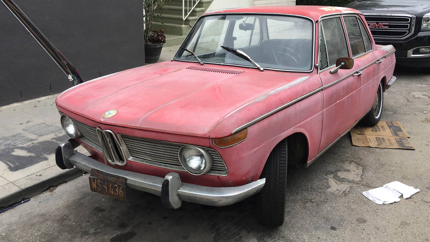 A faded red BMW parked on an LA curb.