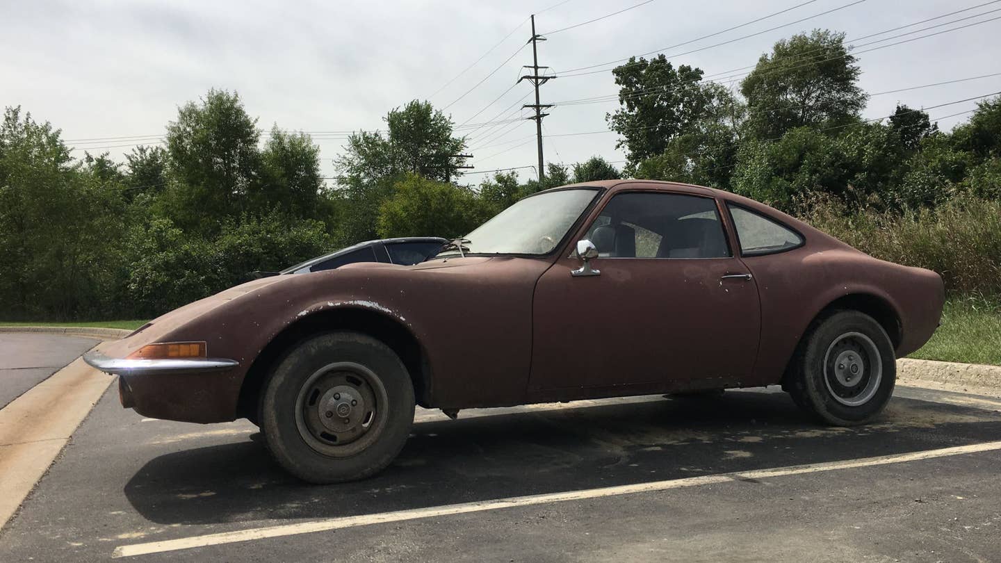 A rusty Opel GT sitting in a parking lot.