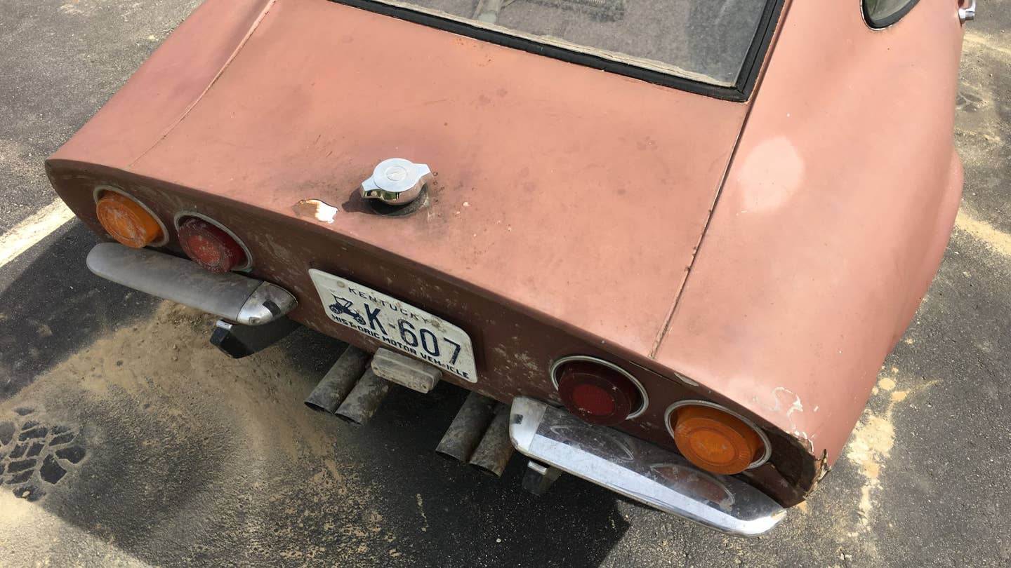 A rusty Opel GT sitting in a parking lot.