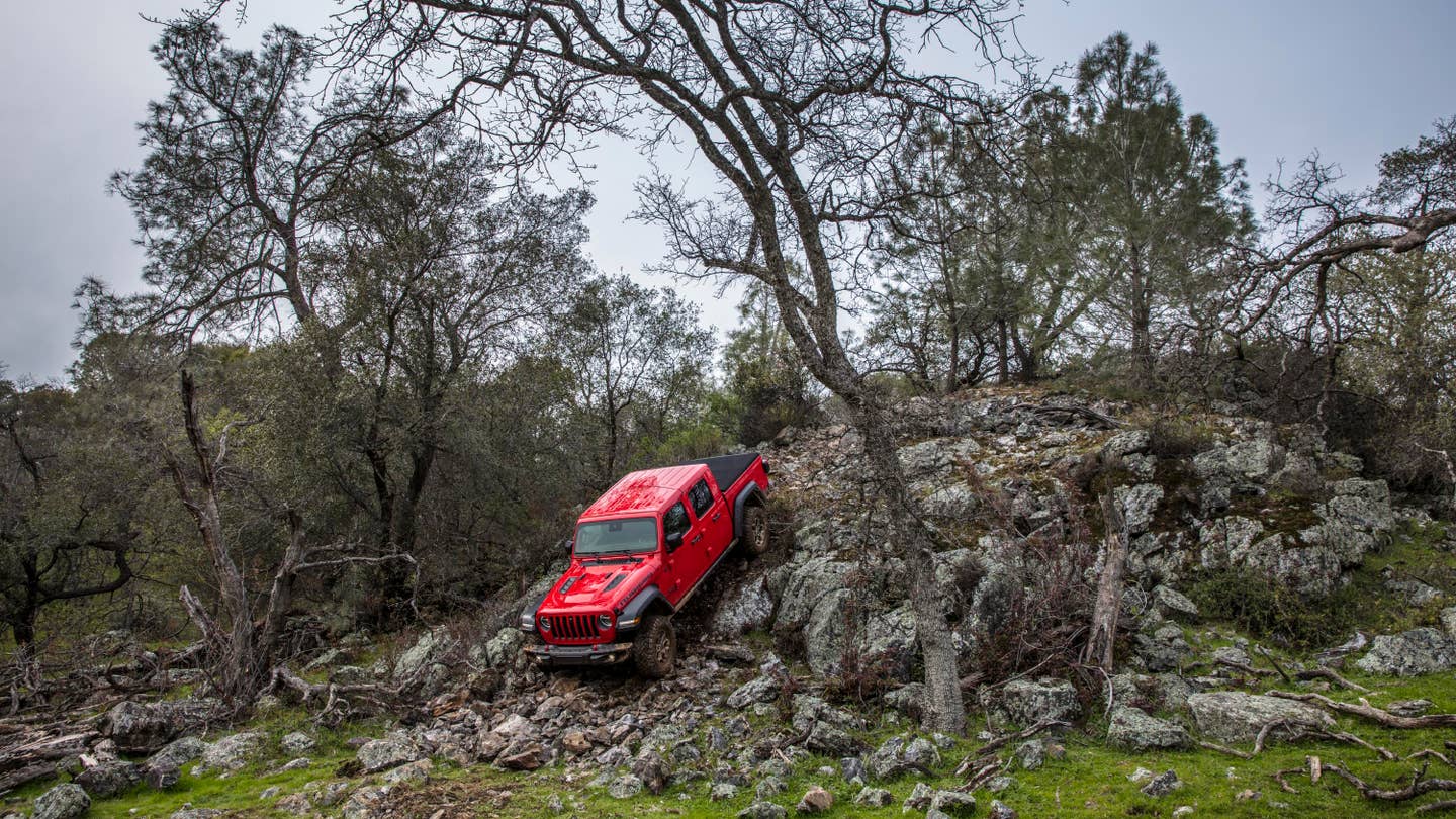 A red Jeep Gladiator crawls down a rocky mountain.