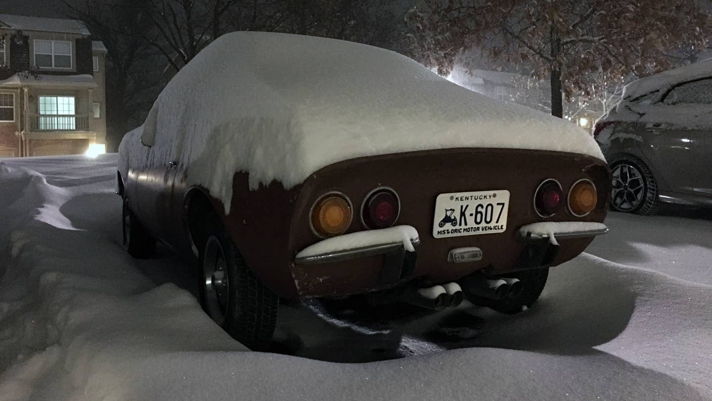 An Opel GT sits in a parking lot buried in snow.
