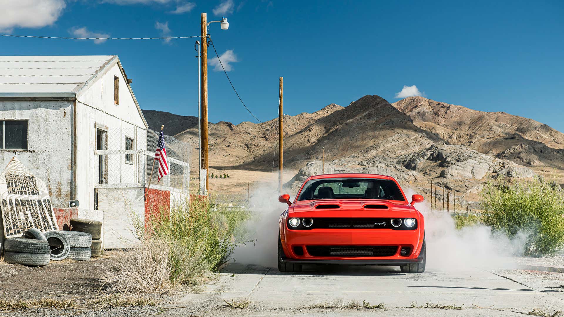 A red Dodge Challenger SRT Hellcat starts a burnout.
