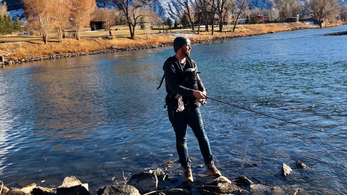 Boots in the icy water, baby in tow, fishing like a boss. 