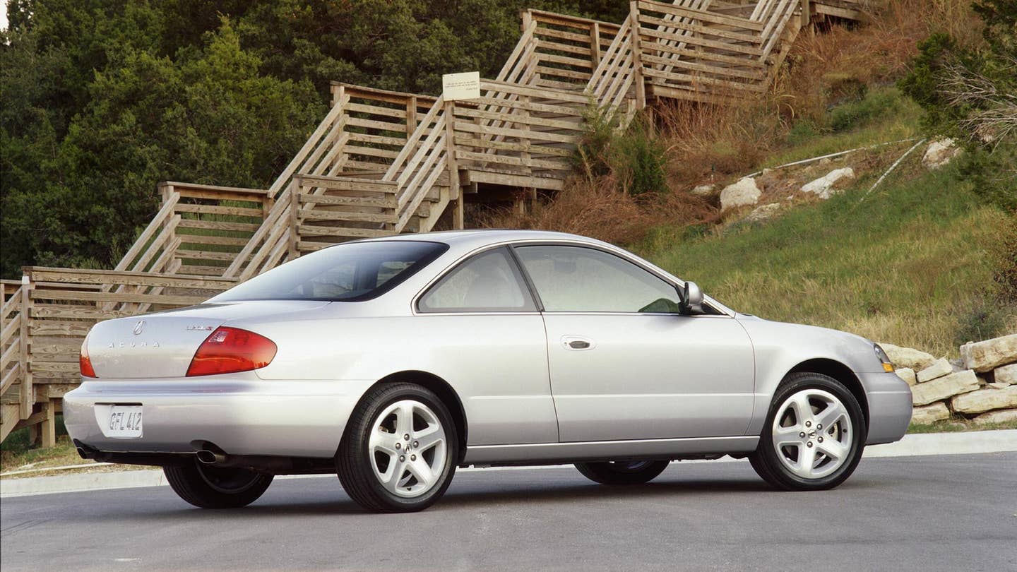 A silver 2001 Acura 3.2CL Type S parked in front of wooden stairs.