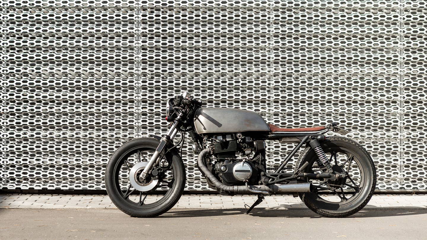 A cafe racer in front of a textured wall.