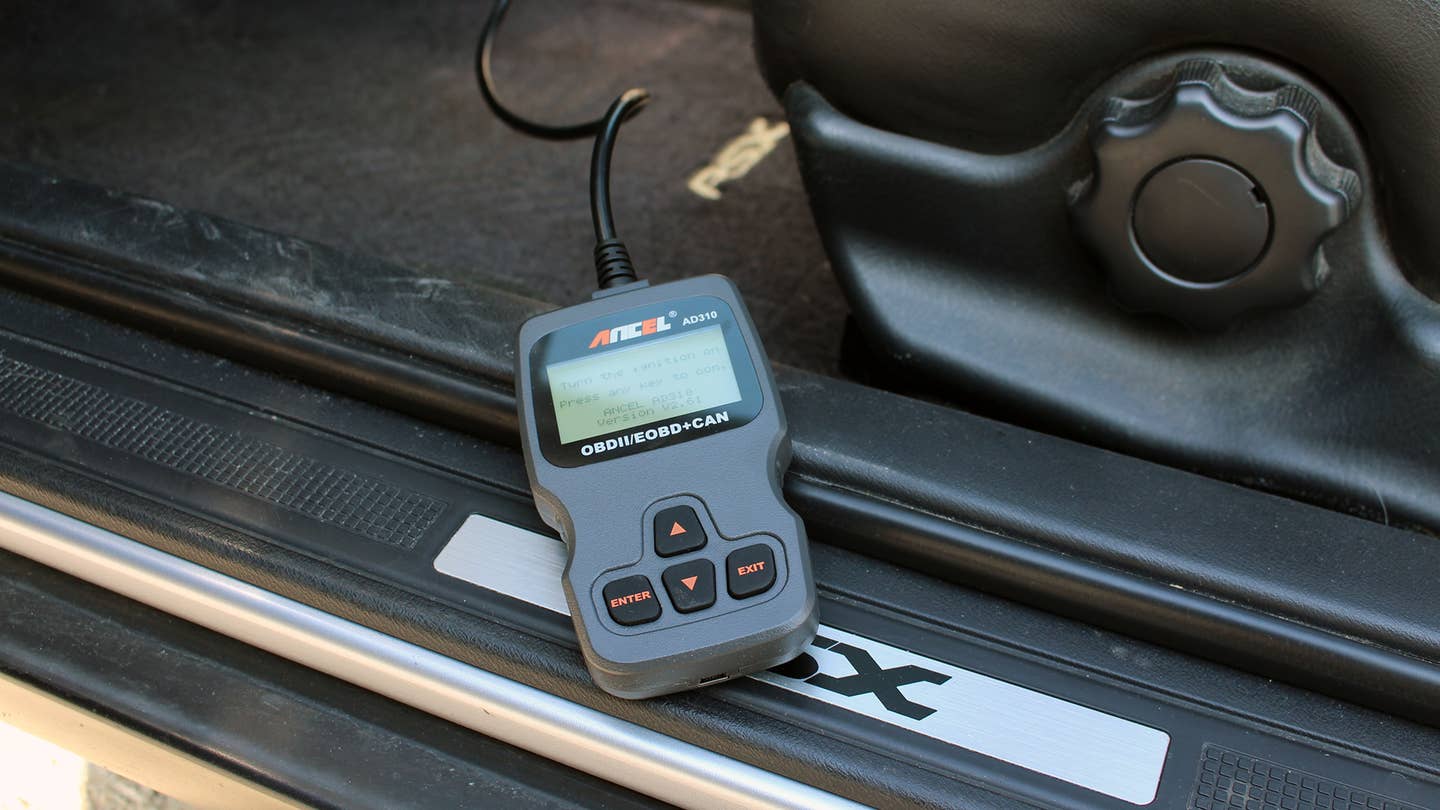 An Ancel OBD scanner in an Acura RSX footwell.
