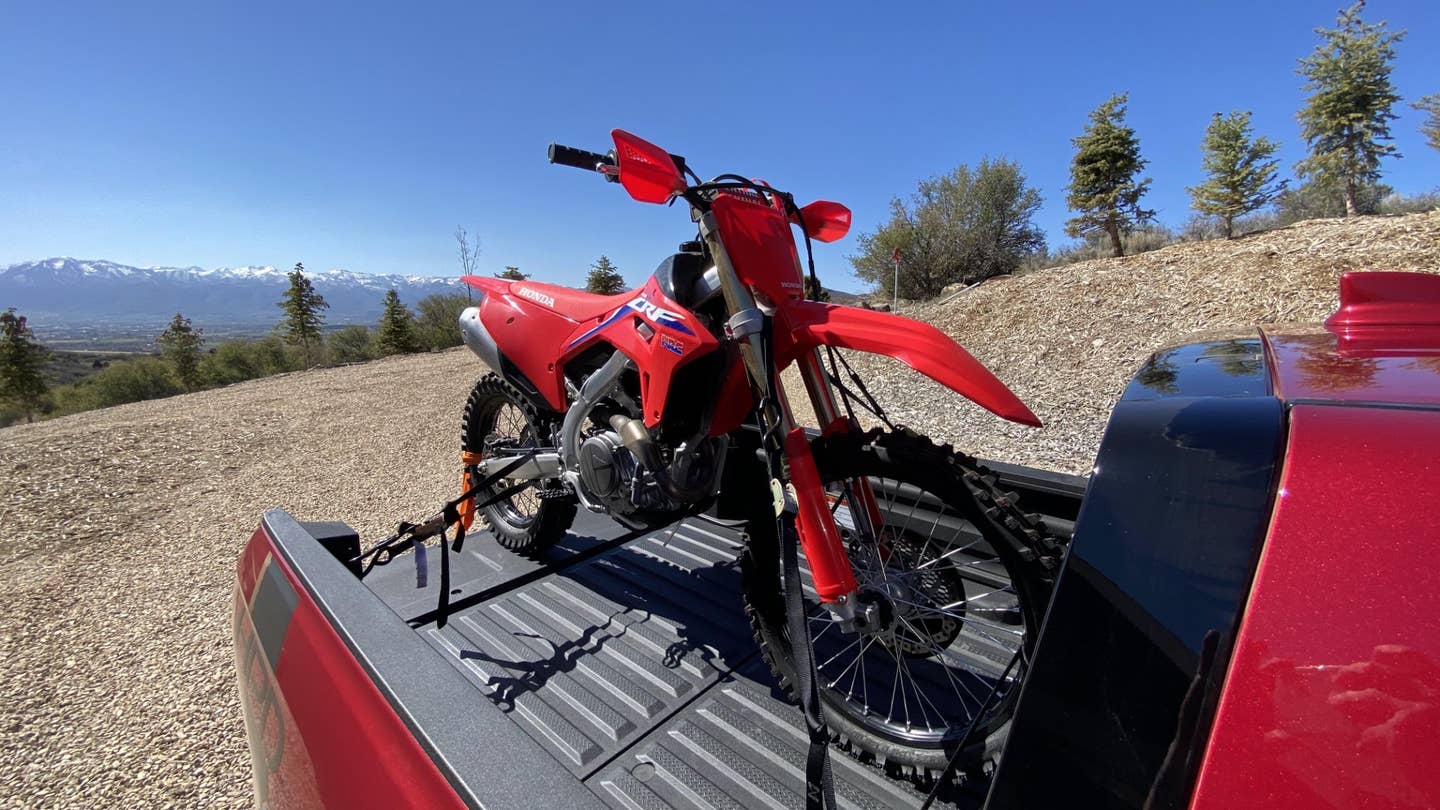 A red CRF450RX strapped in the bed of a 2021 Honda Ridgeline.