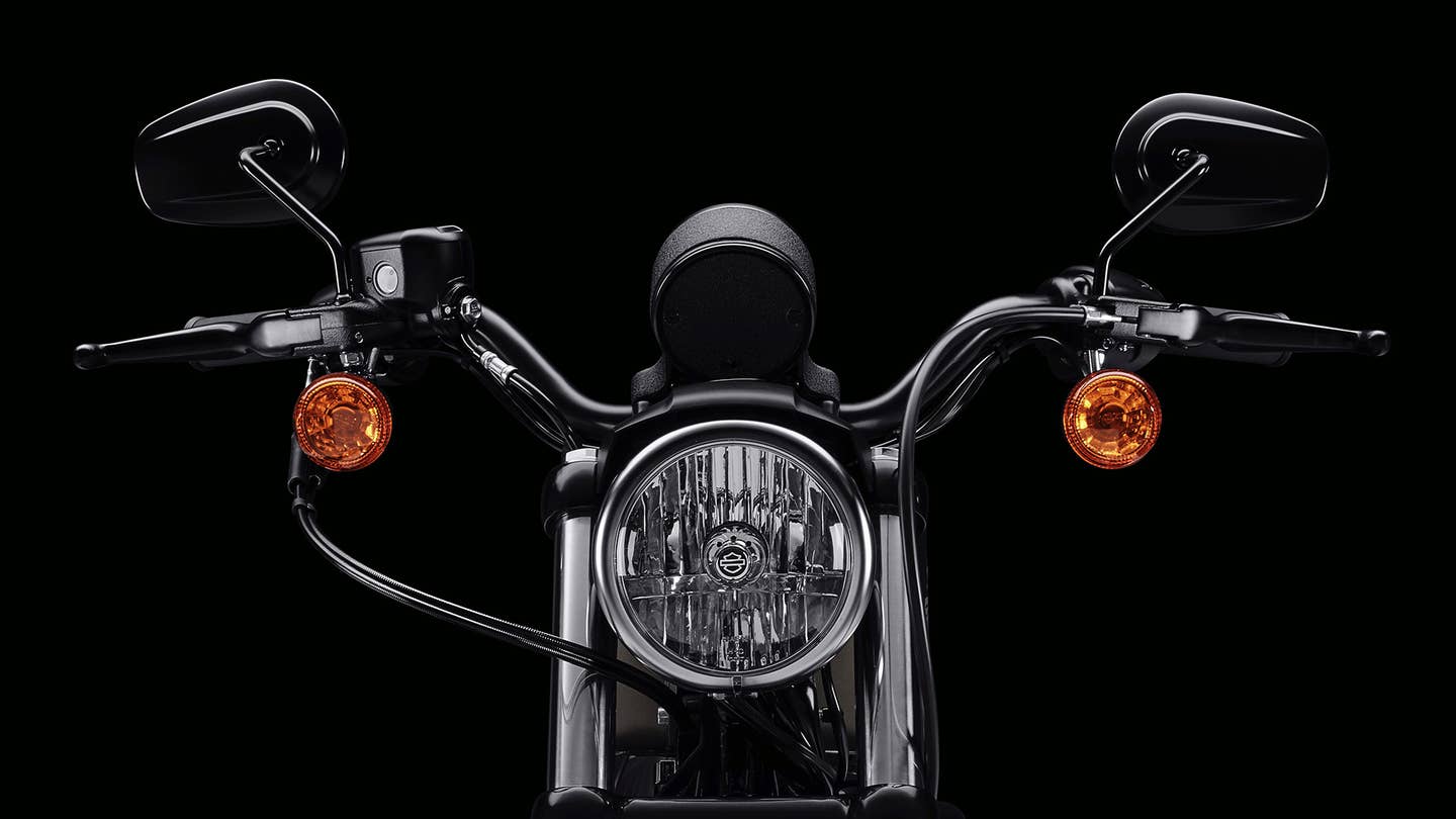 The front headlight, forks, and handlebars on a Harley-Davidson. 