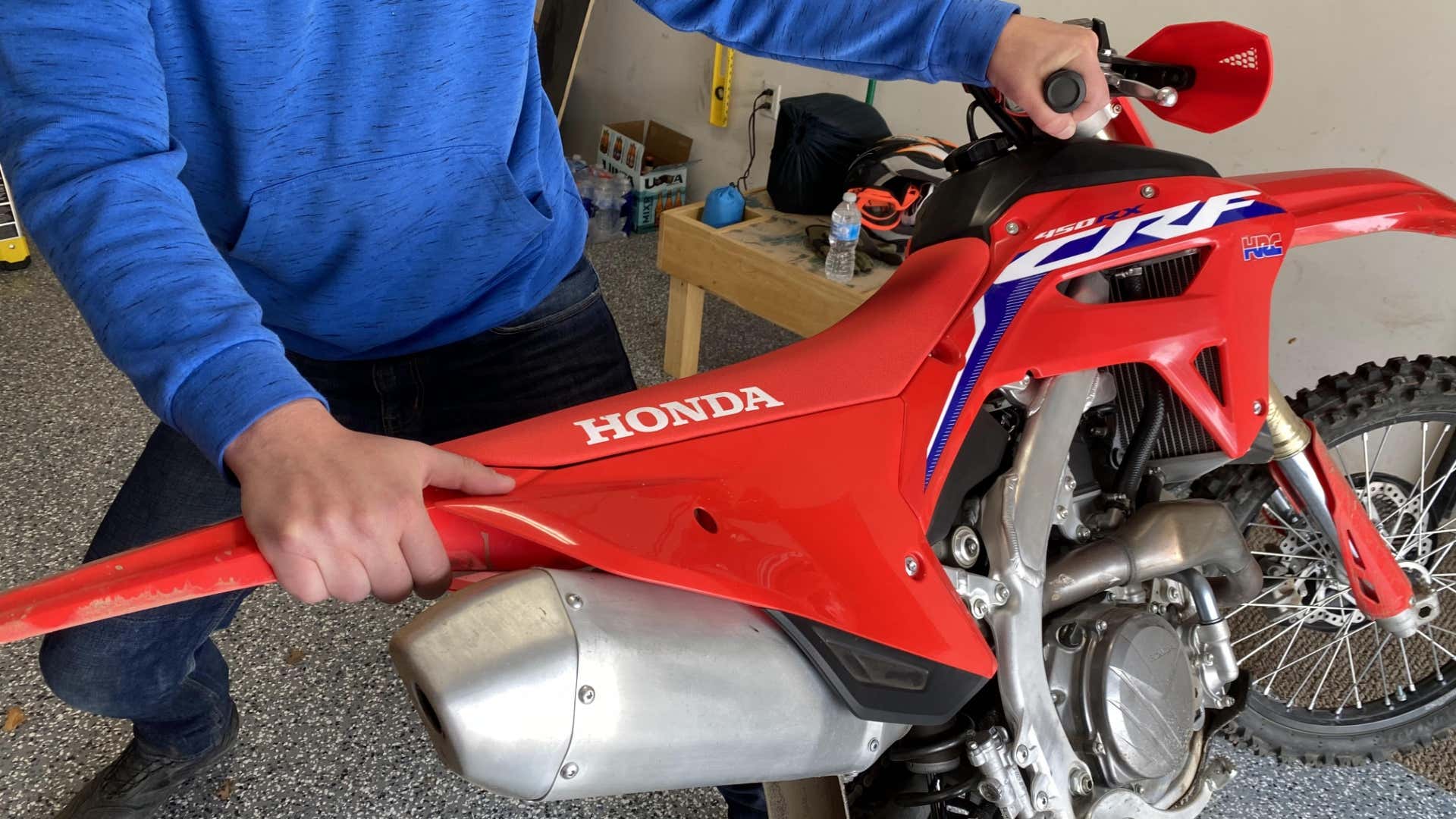 The author's hands on the handlebar and rear fender of the CRF450RX.