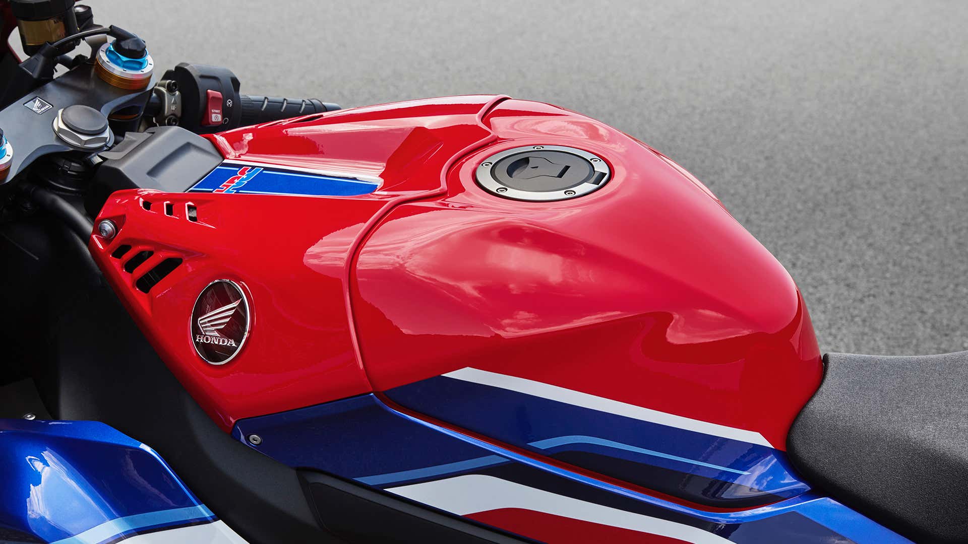 A close-up of the gas tank on a red, white, and blue Honda CBR sport bike.