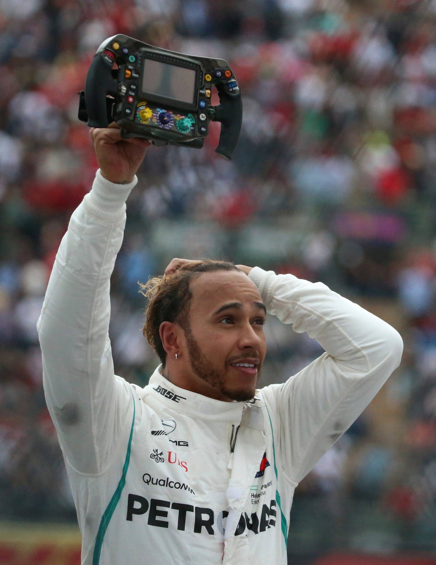 Sir Lewis Hamilton holding up his Mercedes-AMG Petronas steering wheel.