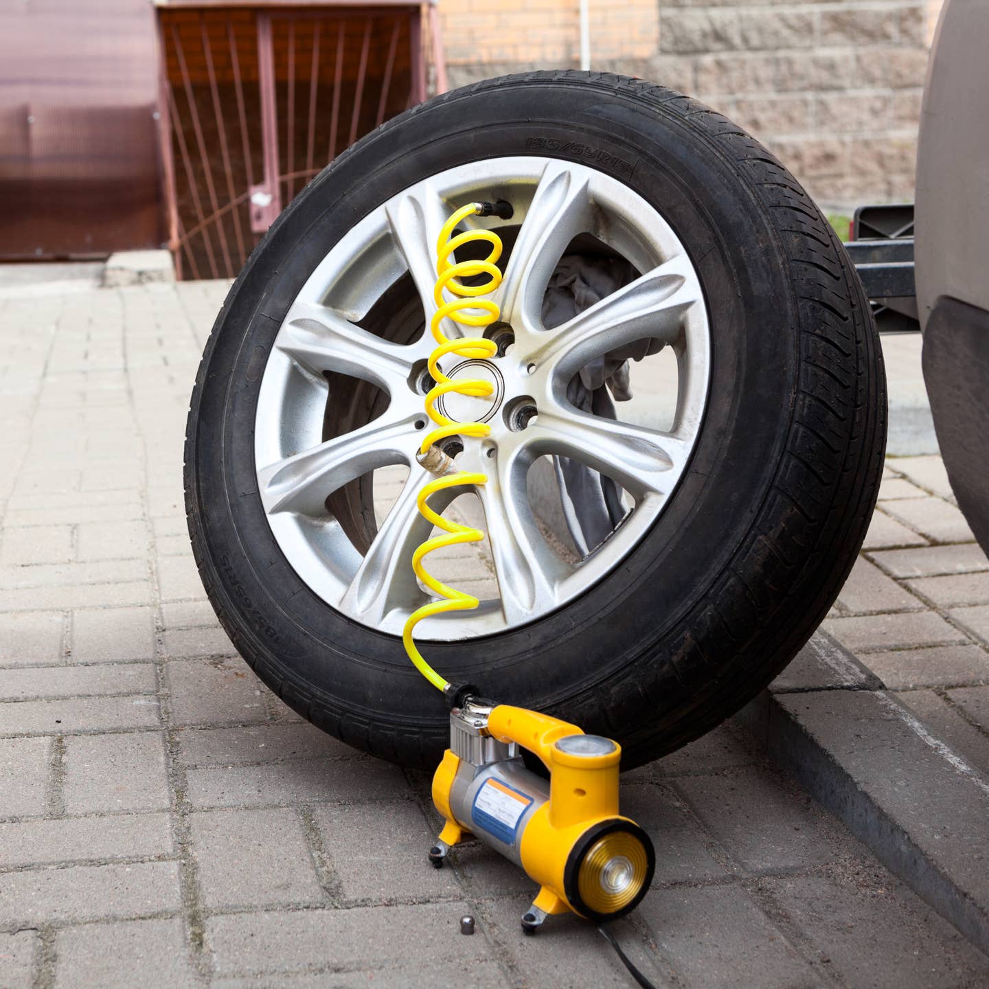 A yellow tire inflator filling a tire off of its vehicle.