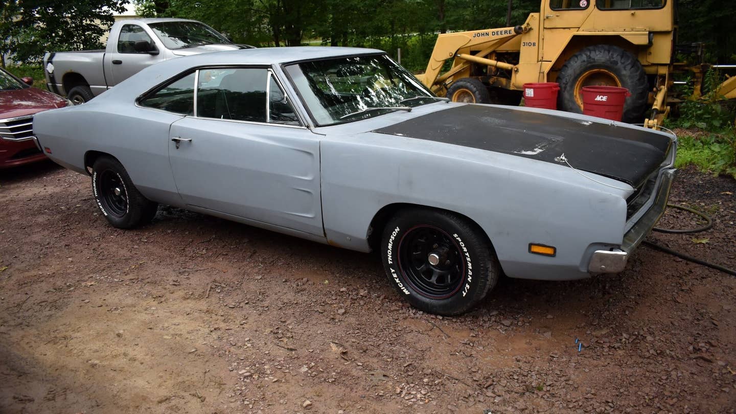 A classic Dodge Charger on a dirt parking lot.