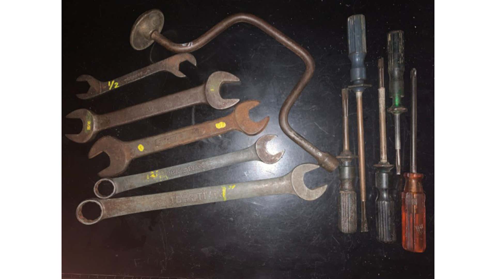 Old wrenches and screwdrivers on a black table.