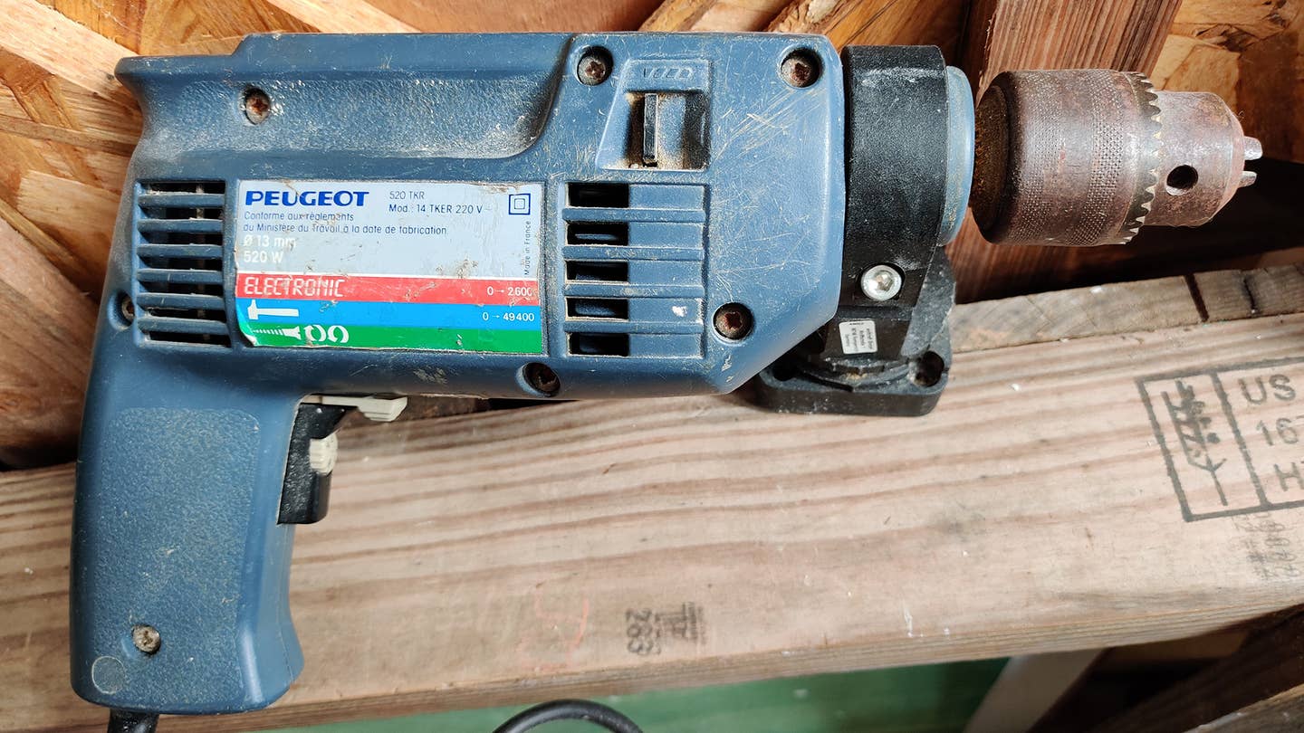 A blue Peugeot power drill on a wooden table.