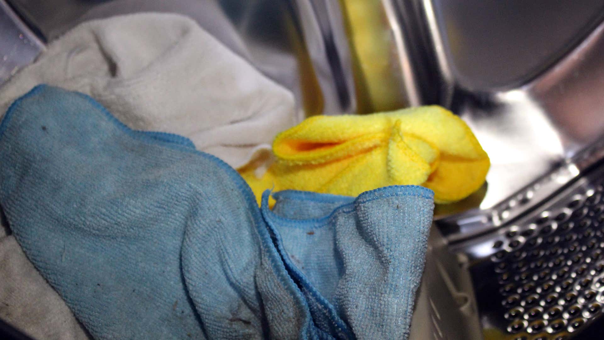 Blue, yellow, and white microfiber towels in a washing machine tub.
