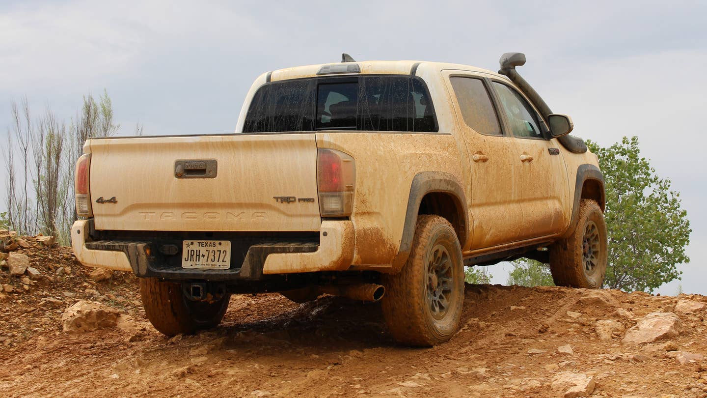 A white Toyota Tacoma TRD Pro gets muddy on a dirt trail.