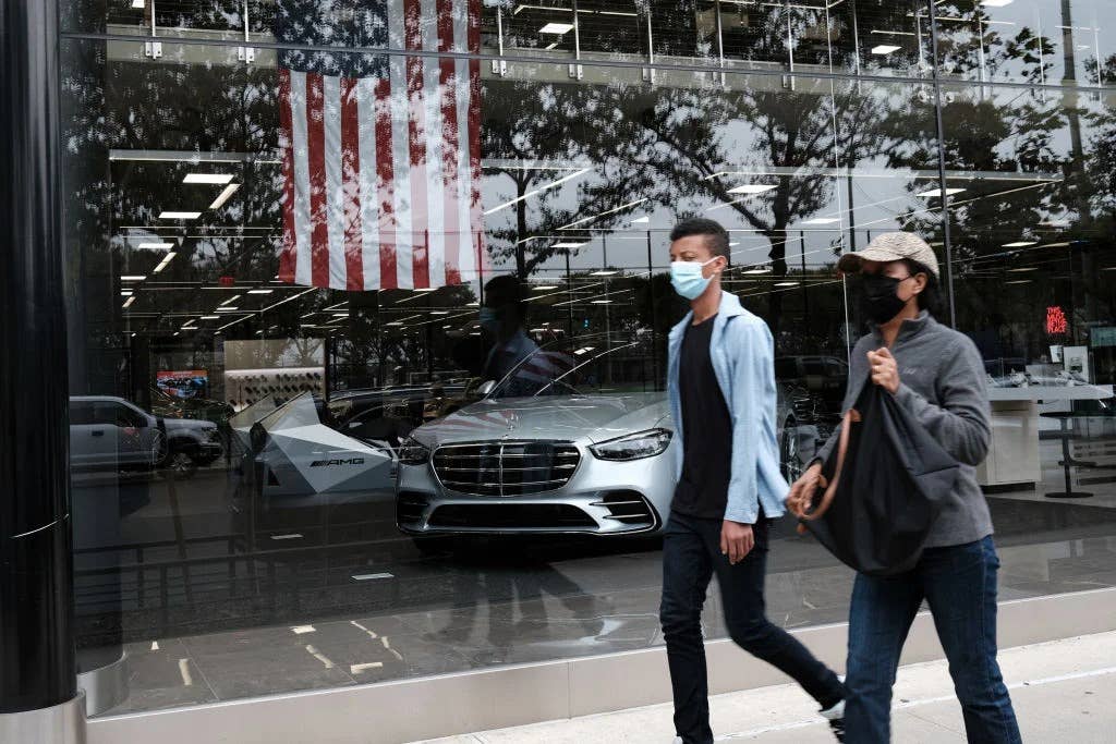 People walking by the squeaky-clean window of a Mercedes-Benz store.