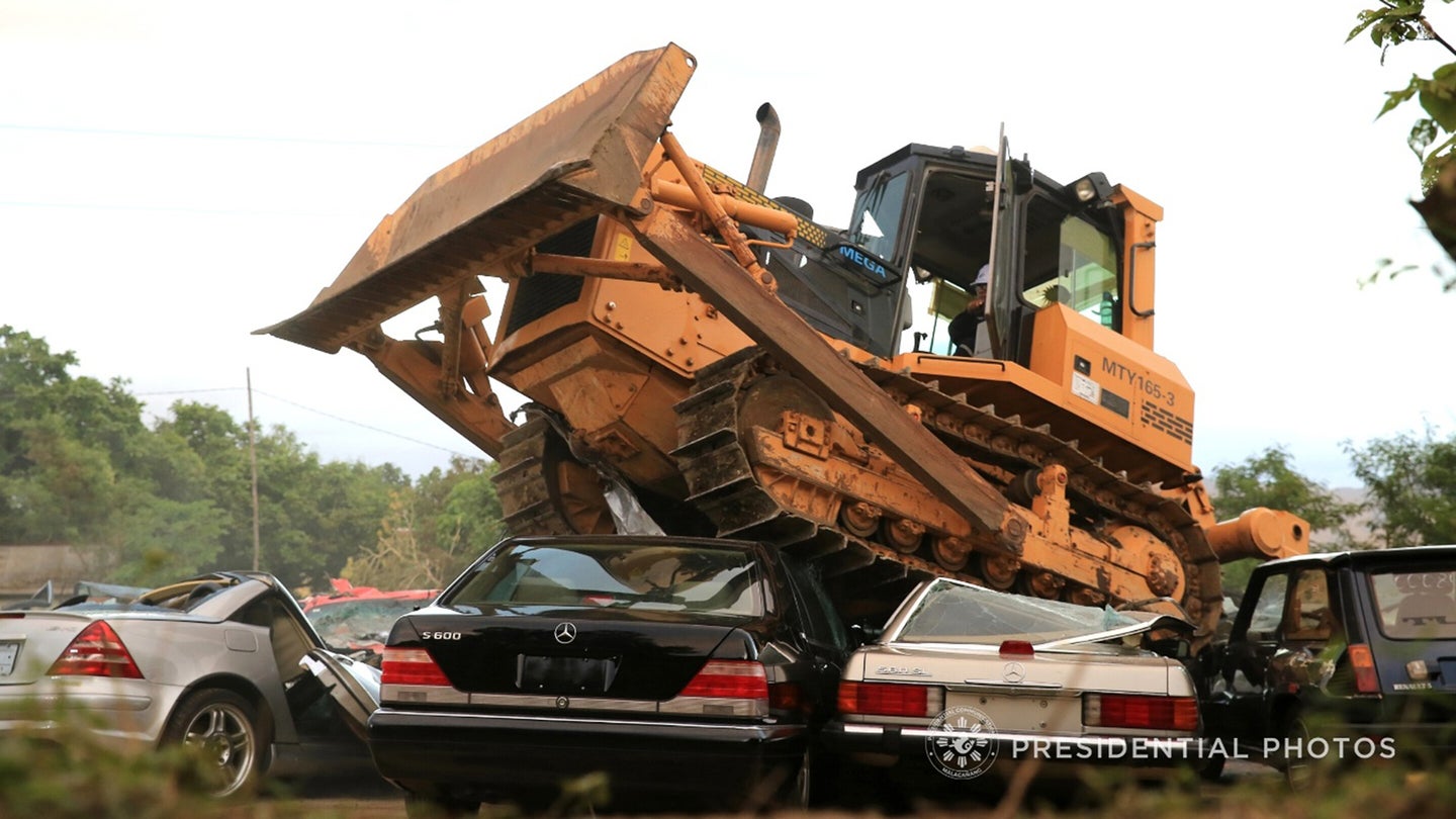 A bulldozer runs over 14 smuggled luxury vehicles as President R