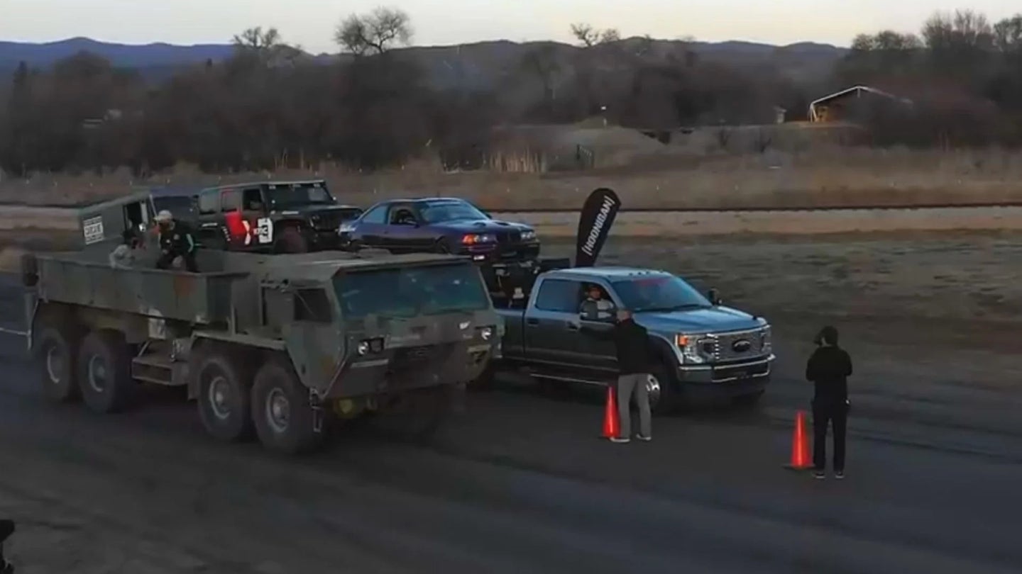 Watch an 8×8 HEMTT Military Truck Drag Race a Ford F-450 Towing Three Cars