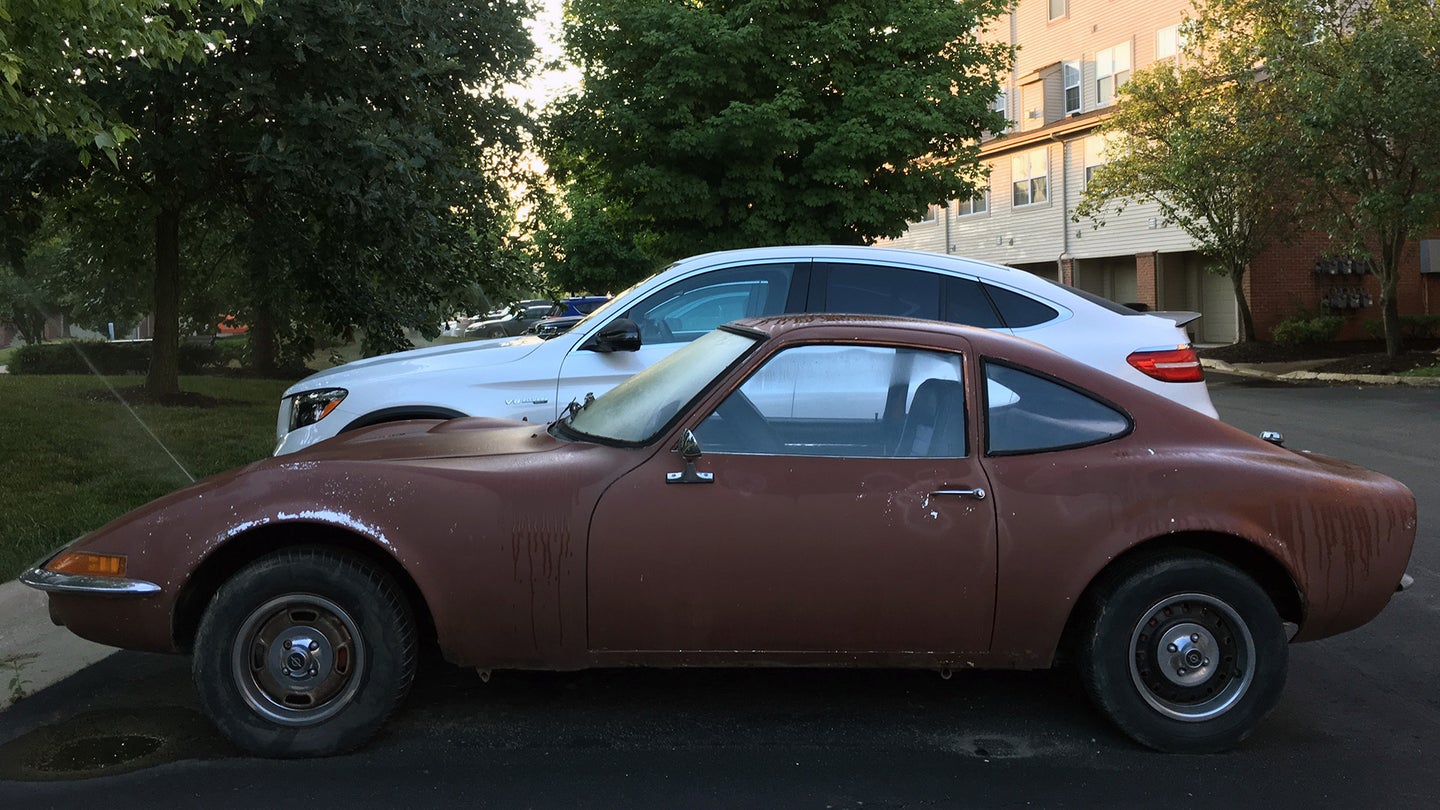 A brown Opel GT parked next to a Mercedes-AMG crossover coupe.