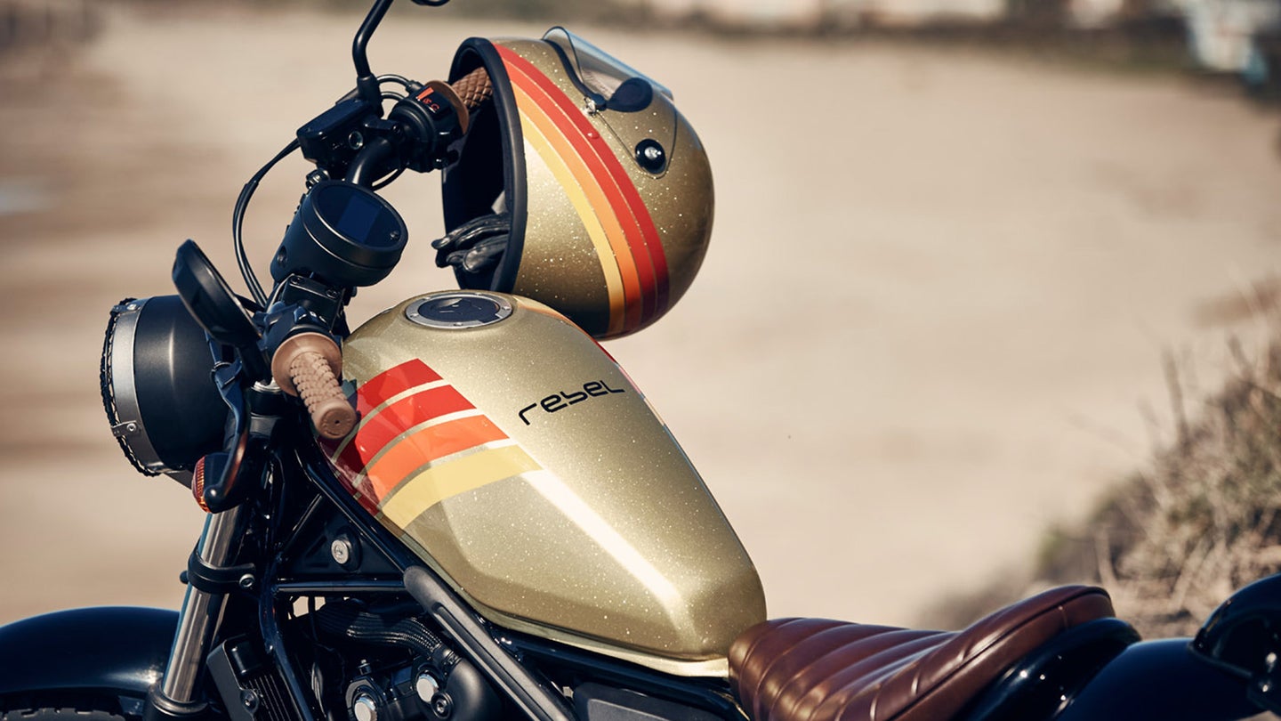A gold motorcycle gas tank with retro stripes and a matching gold helmet.