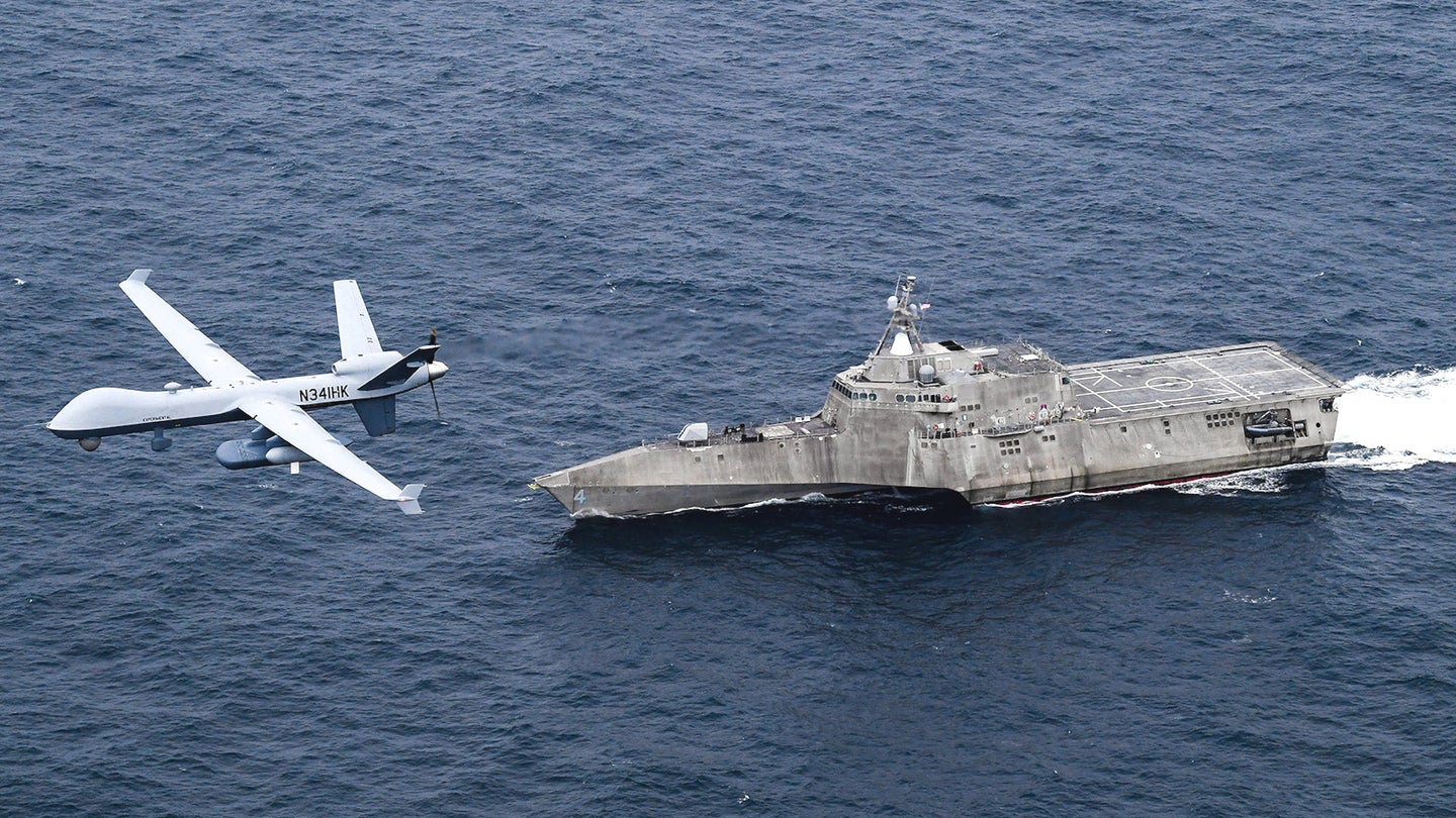 A General Atomics MQ-9B Sea Guardian drone flies above the Independence class Littoral Combat Ship USS Coronado during the Unmanned Integrated Battle Problem 21 experiment.