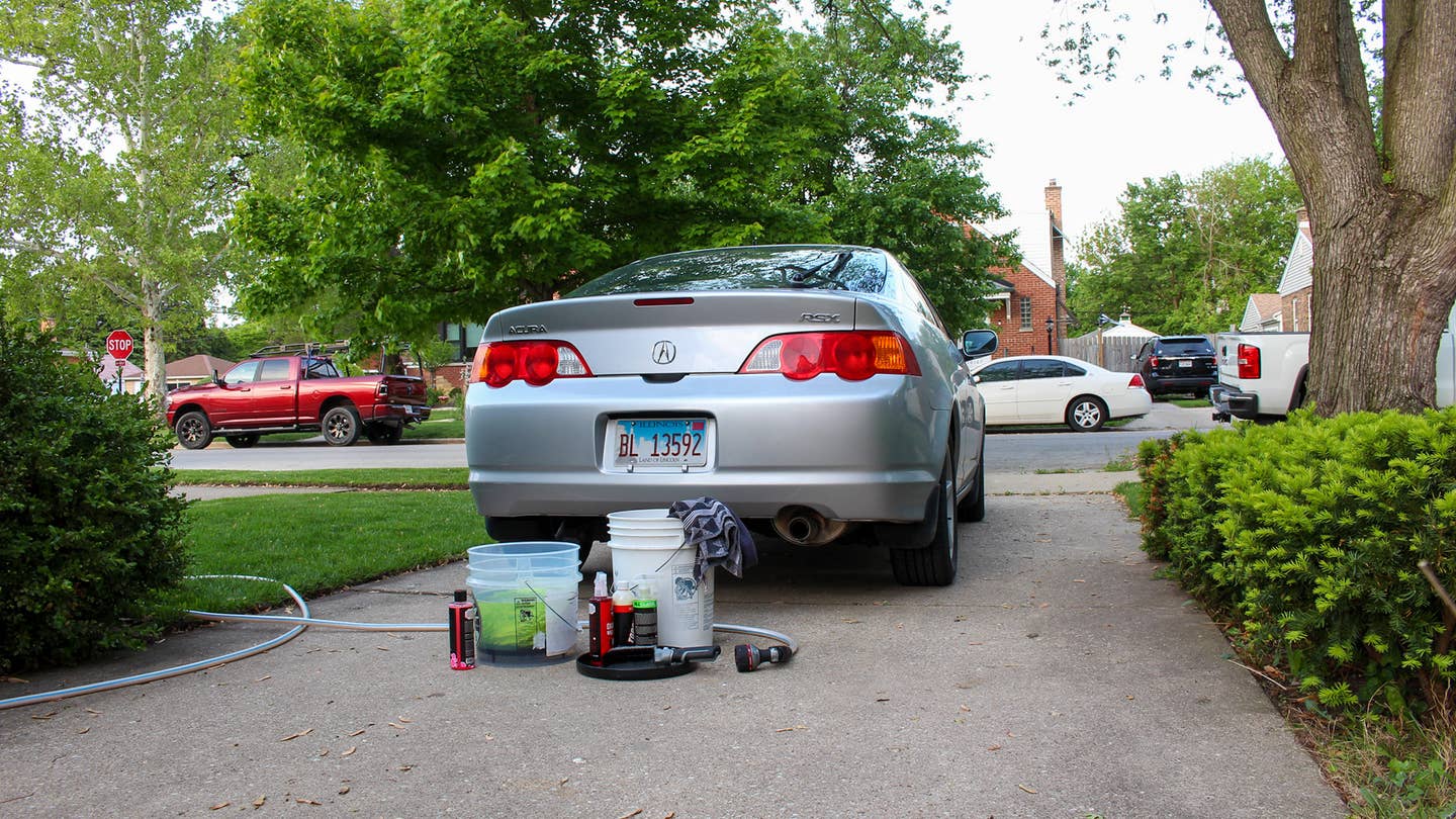 An Acura RSX in a driveway with car wash equipment.