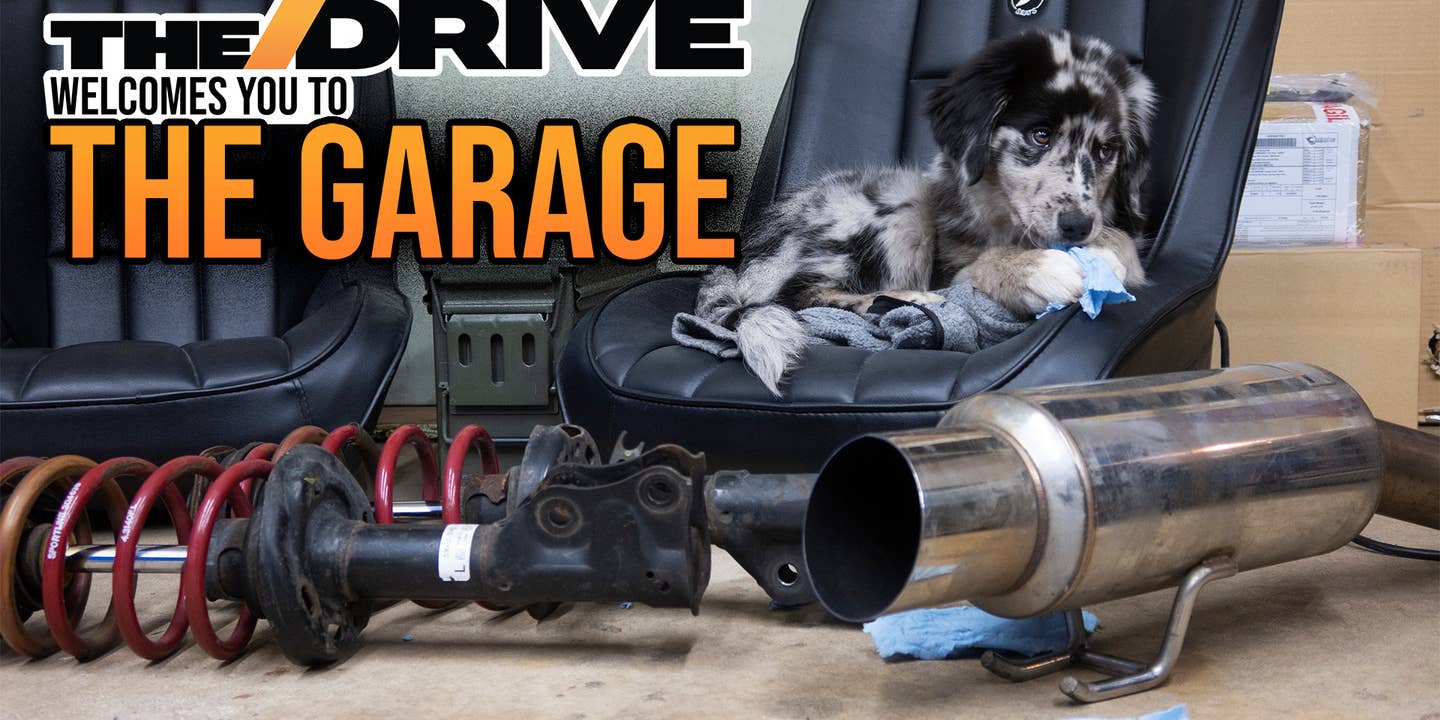 A collection of car parts, with a soft and fluffy dog sitting among them.
